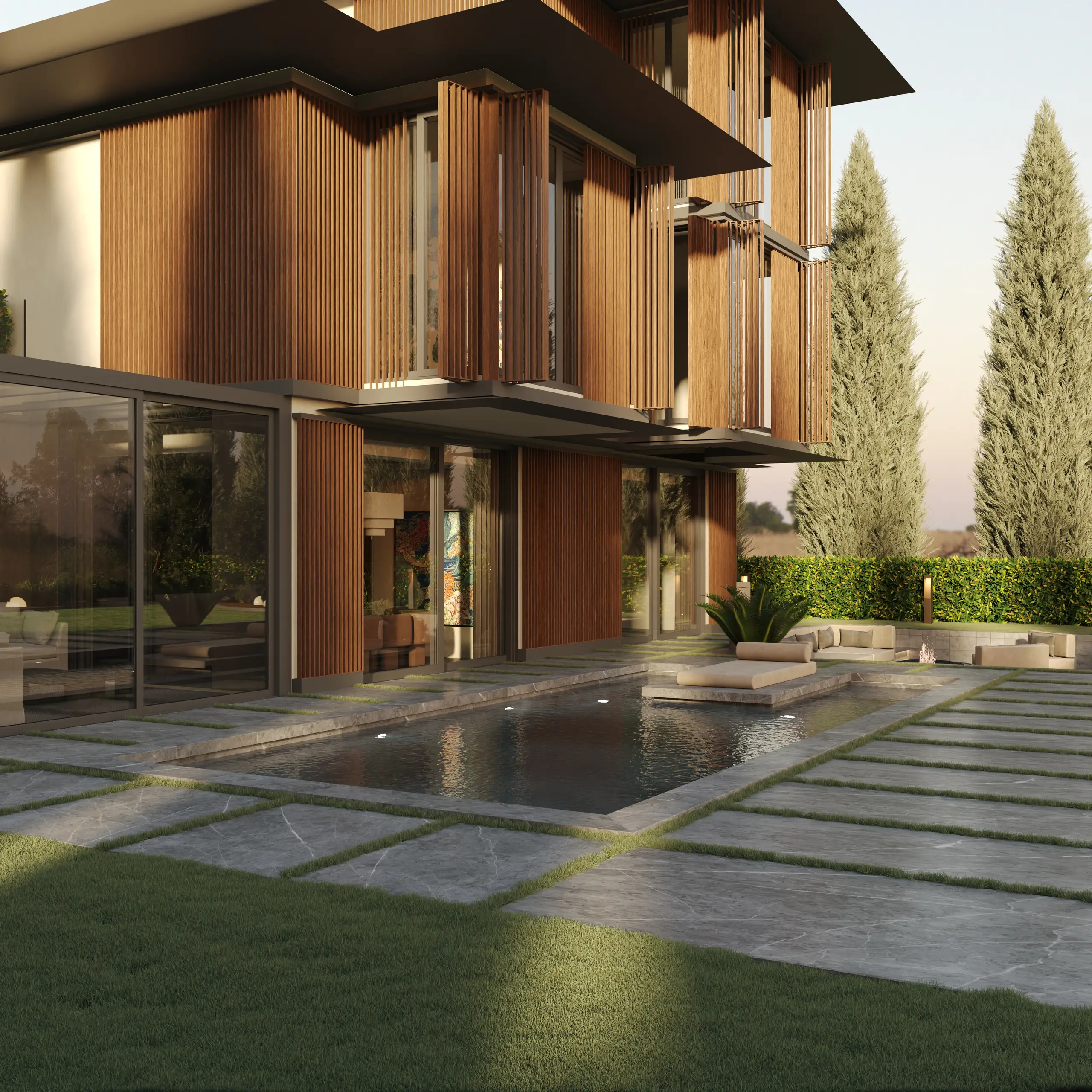 Villa corner and reflecting pool on a stone paved terrace, lit by low golden evening sun.