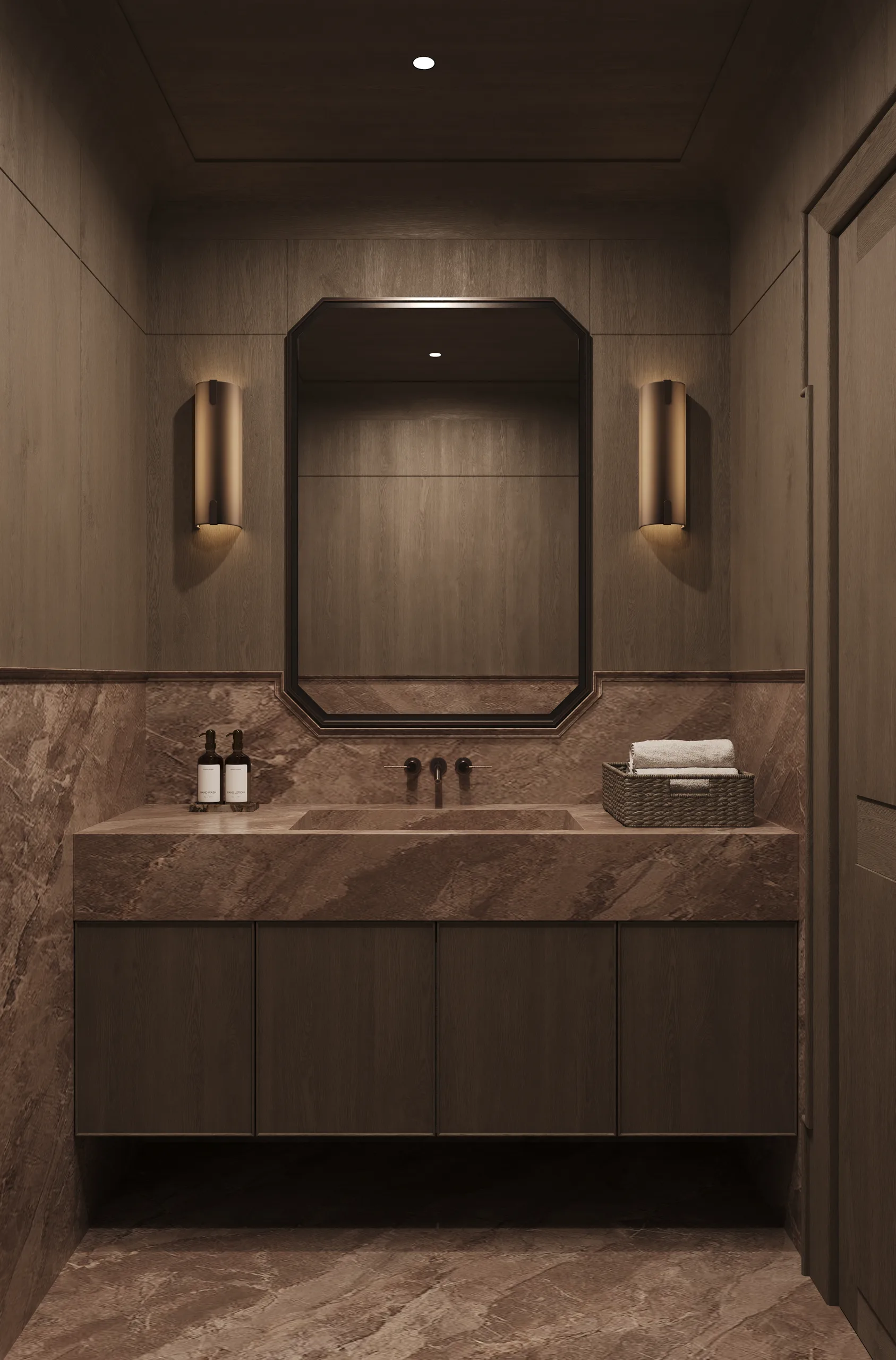 Guest powder room clad in rose marble, with an octagonal black mirror and brass wall sconces.